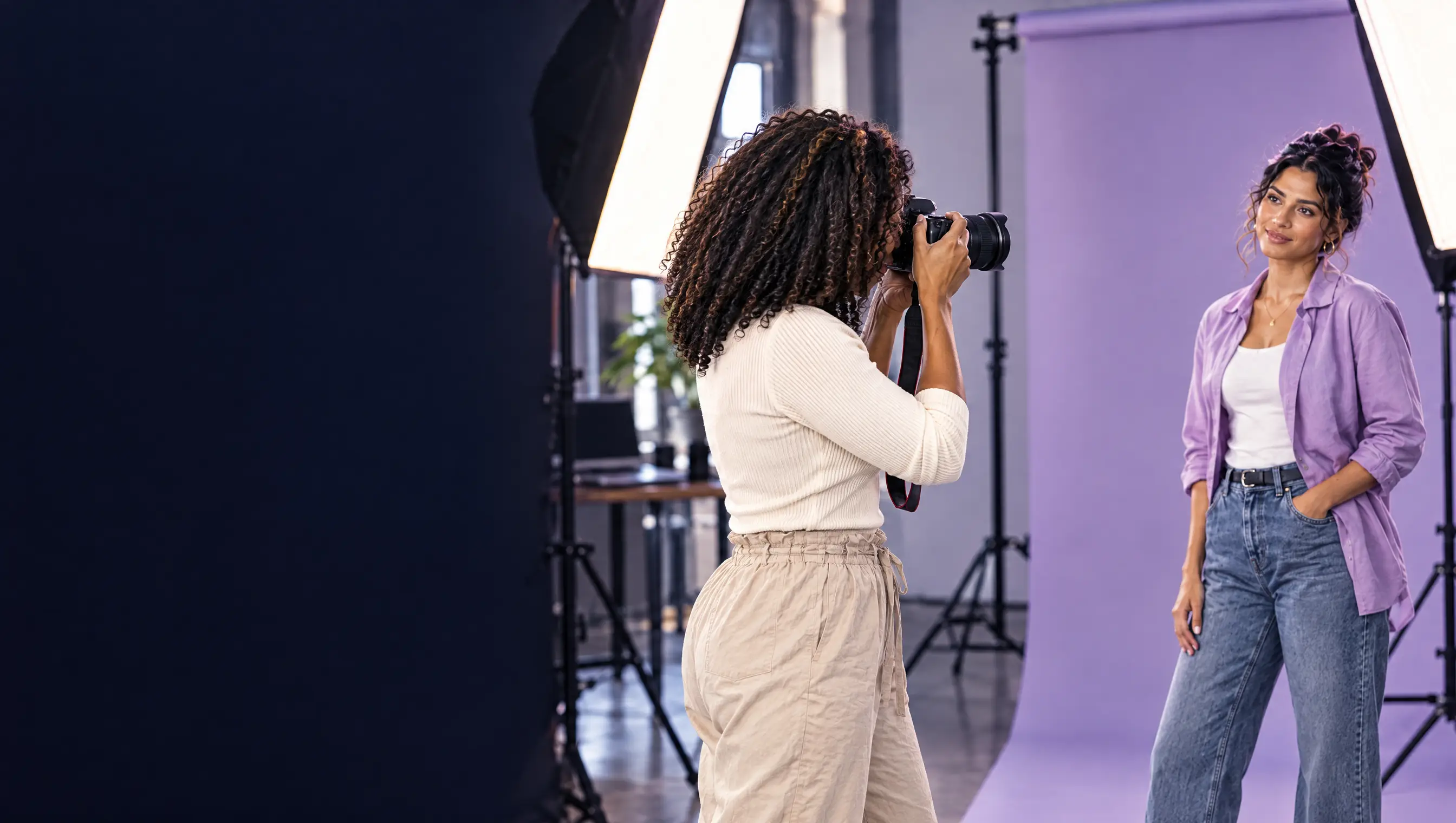 Eine Fotografin fotografiert mit der Kamera am Auge ein posierendes Model im Studio.